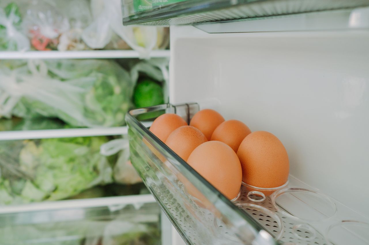 Refrigerator door open with eggs in shelf container