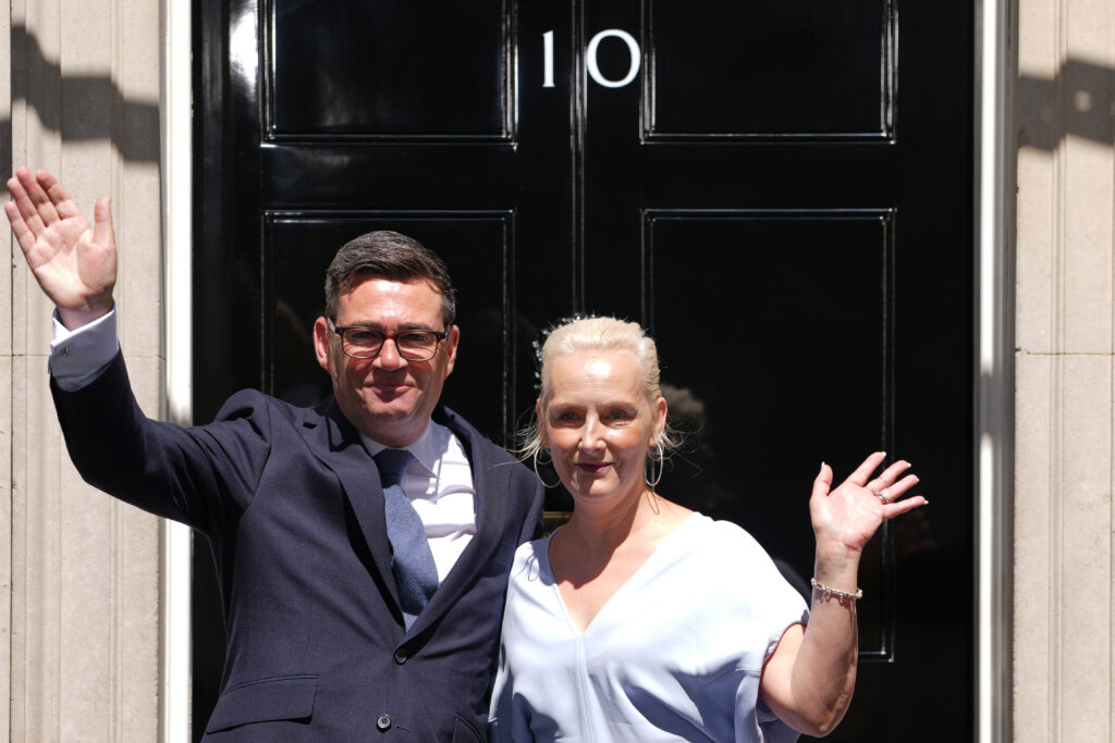 A man in a suit and a woman wave outside the door of 10 Downing Street in London