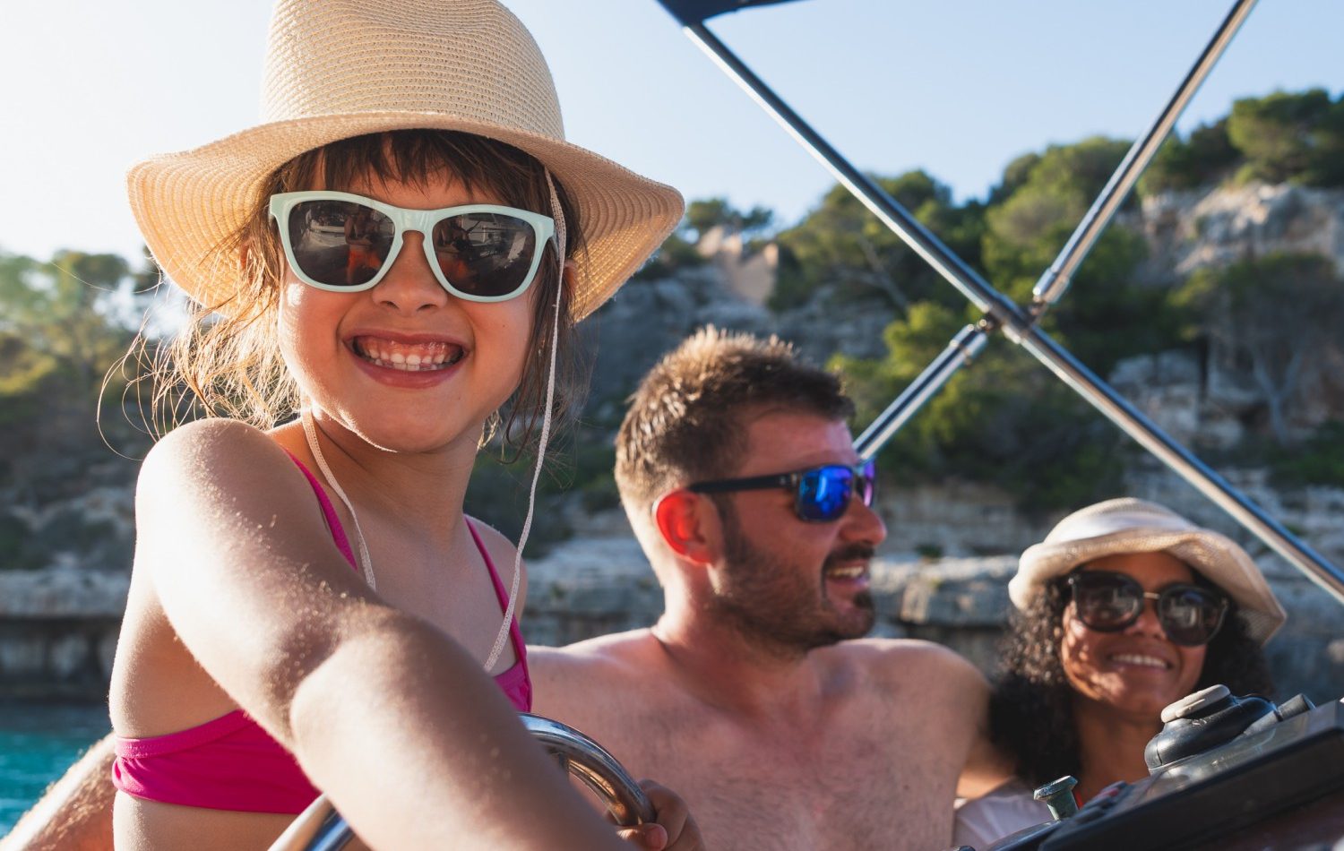 Smiling girl at boat helm with family enjoying sunny day. Summer, vacation, boat concept