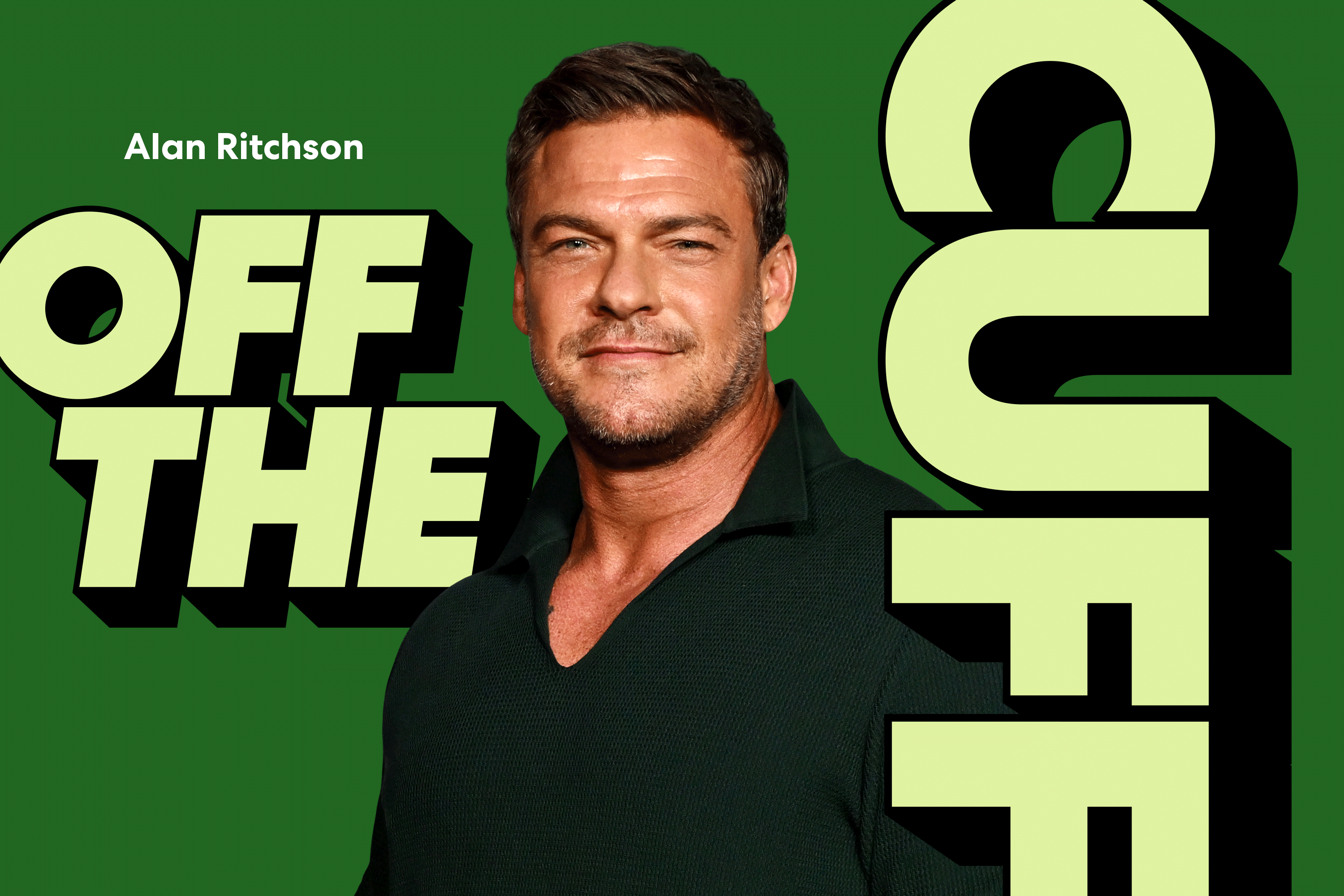 Actor Alan Ritchson standing in front of a green background with the words