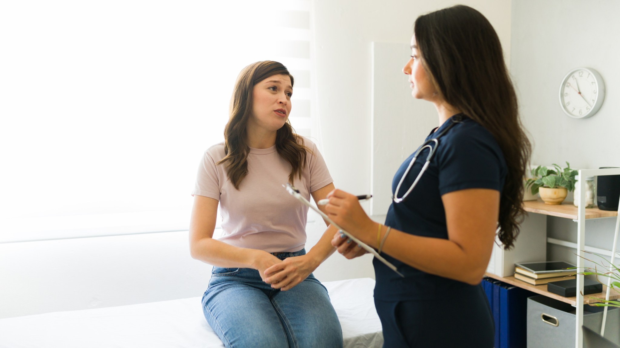 Woman speaking to a doctor who is taking notes.