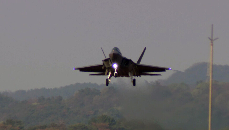 KF-21 Boramae fighter jet flying low over a hazy landscape during a test flight.