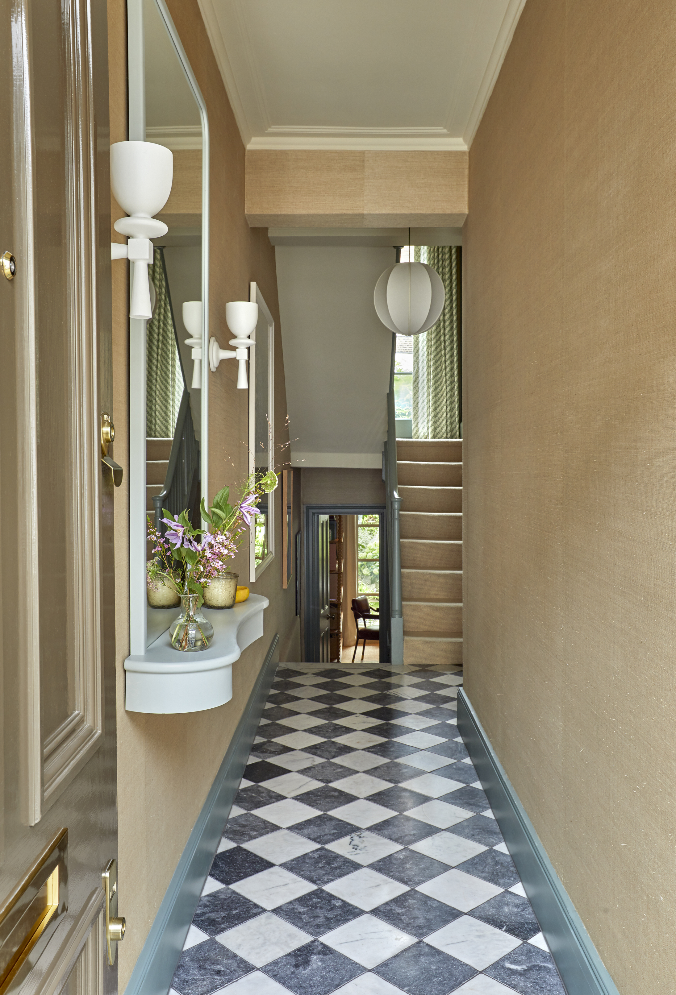 checkerboard tiled entryway with a mirror console by the door