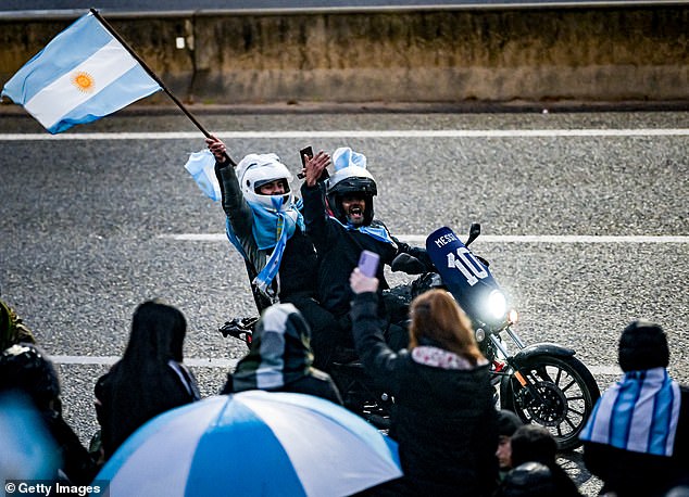 Fans of Argentina cheer while riding a motorcycle, as other fans wait for players and coaching staff of Argentina at Predio Lionel Andres Messi after losing the FIFA World Cup 2026 final against Spain, on July 20, 2026 in Ezeiza, Argentina