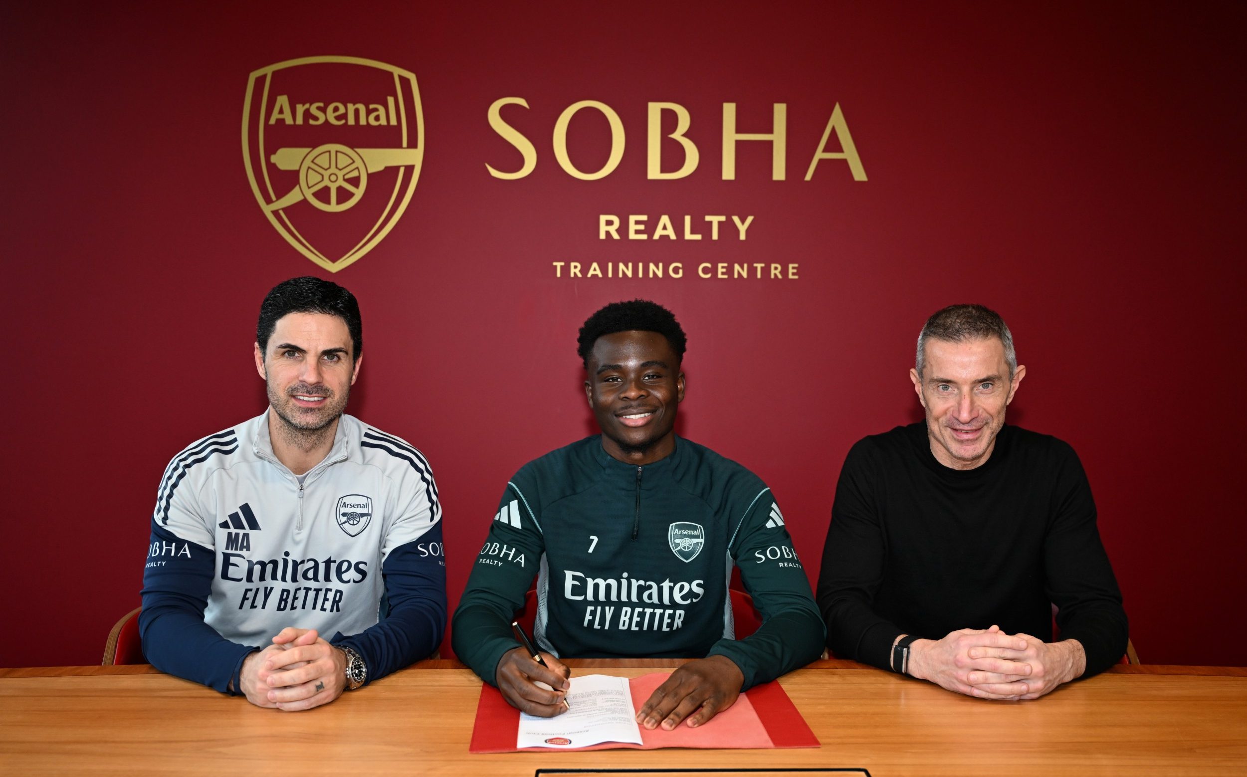 Bukayo Saka (centre) poses for pictures with Mikel Arteta (left) and Andrea Berta at the Sobha Realty Training Centre after signing a new contract in February