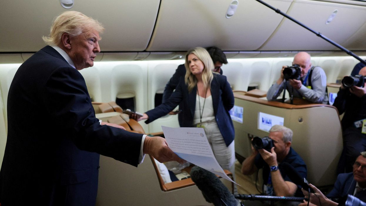 U.S. President Donald Trump makes reference to a printed copy of one of his Truth Social posts as he speaks to reporters mid-flight in the press cabin of the new, Qatari-gifted Air Force One, after changing planes to return to Washington from RAF Mildenhall, Britain, July 8, 2026. REUTERS/Jonathan Ernst