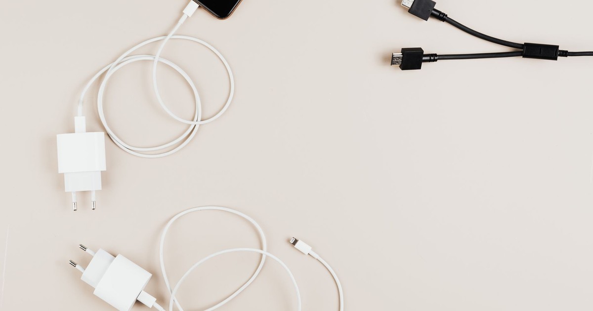 Flat lay of mobile devices with chargers and cables on a neutral background.