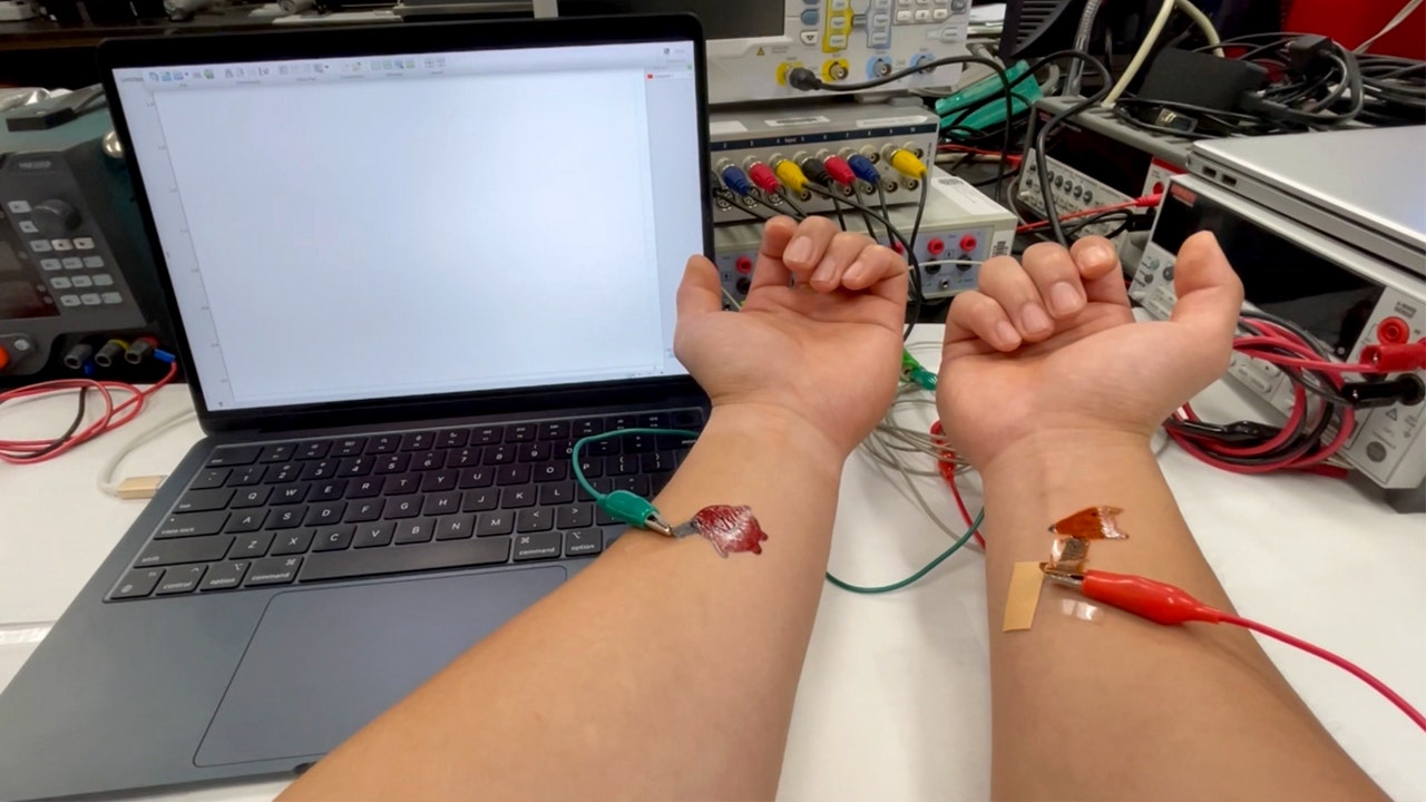 Wires are attached to two arms with painted tattoos.