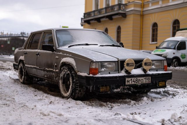 Rustic vintage Volvo car parked on a snowy urban street, showcasing winter charm.
