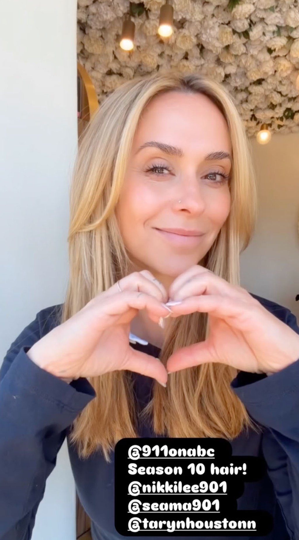 Jennifer Love Hewitt making a heart shape with her hands.