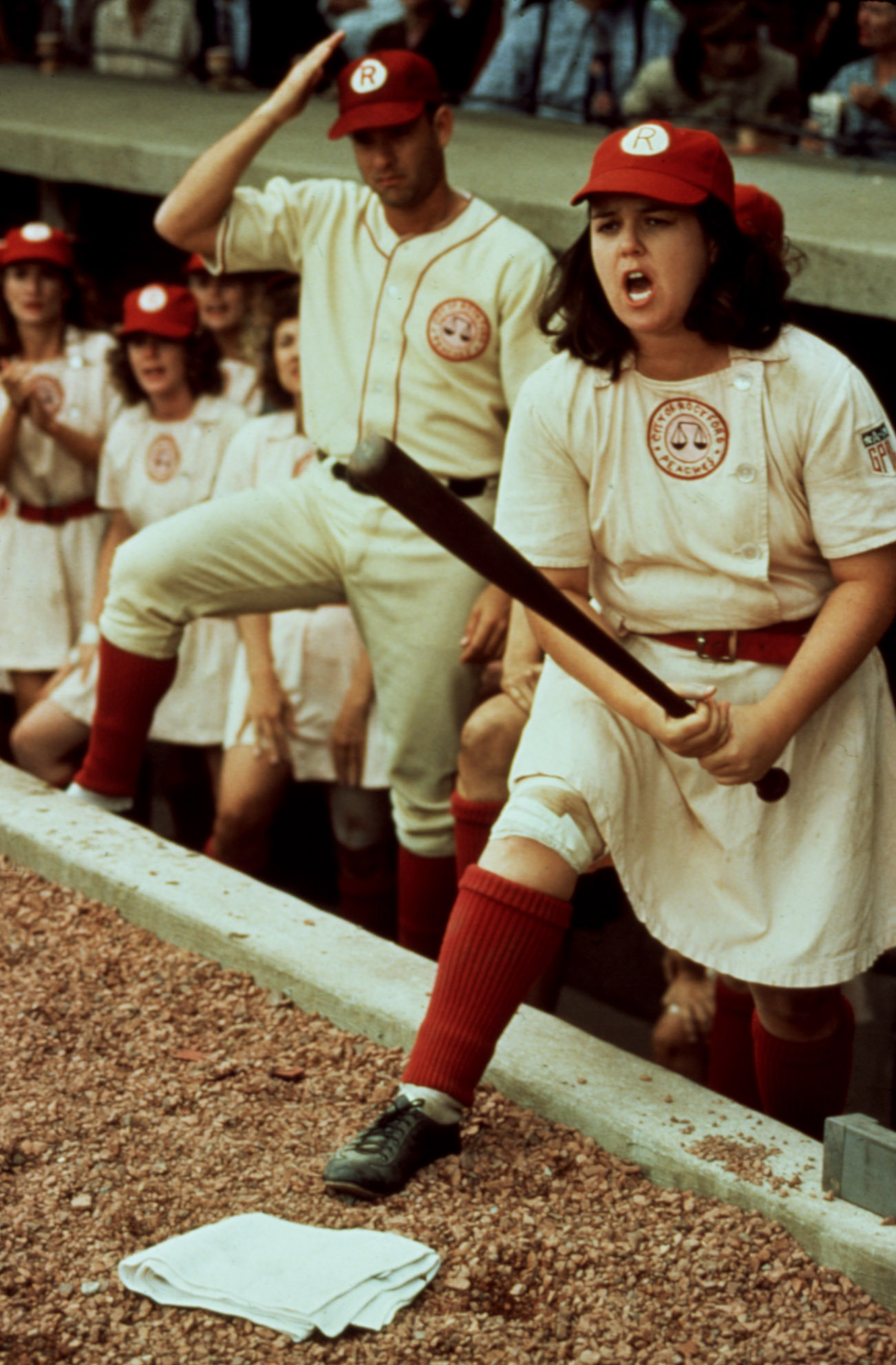 Rosie O'Donnell at bat, with Tom Hanks in the background, in 
