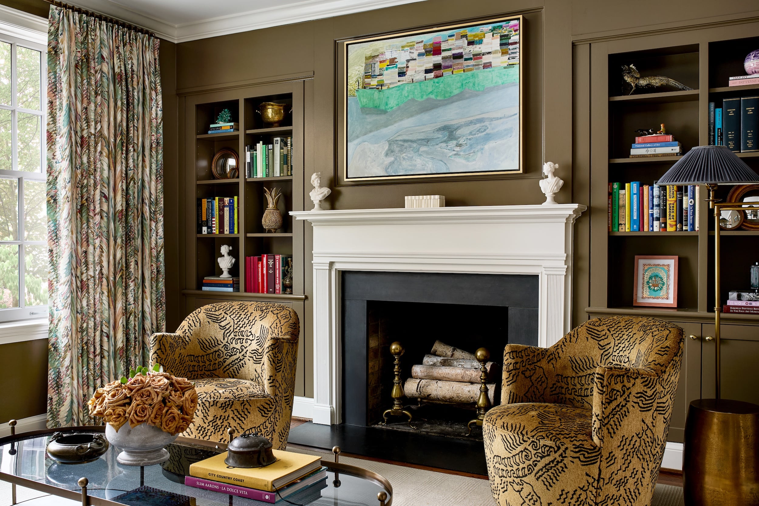 In the den, built-in bookshelves flank Lisa Sanditz’s “Barge/Hudson” painting.