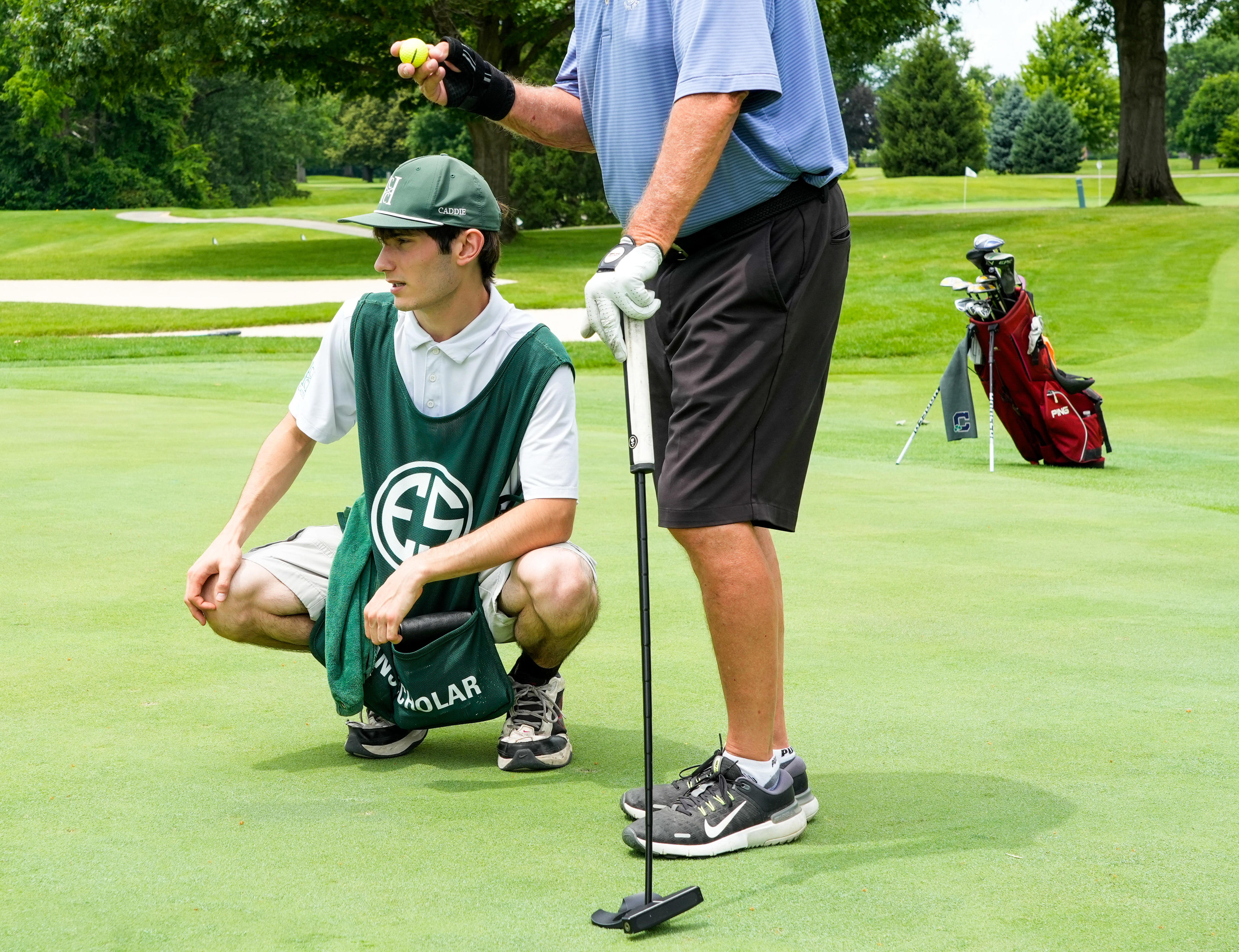 Purdue Polytechnic High School student Bryce Oertel helps Joe Renie, a Western Golf Association director, line up a shot on the green at the Hillcrest Country Club where Oertel caddies.
