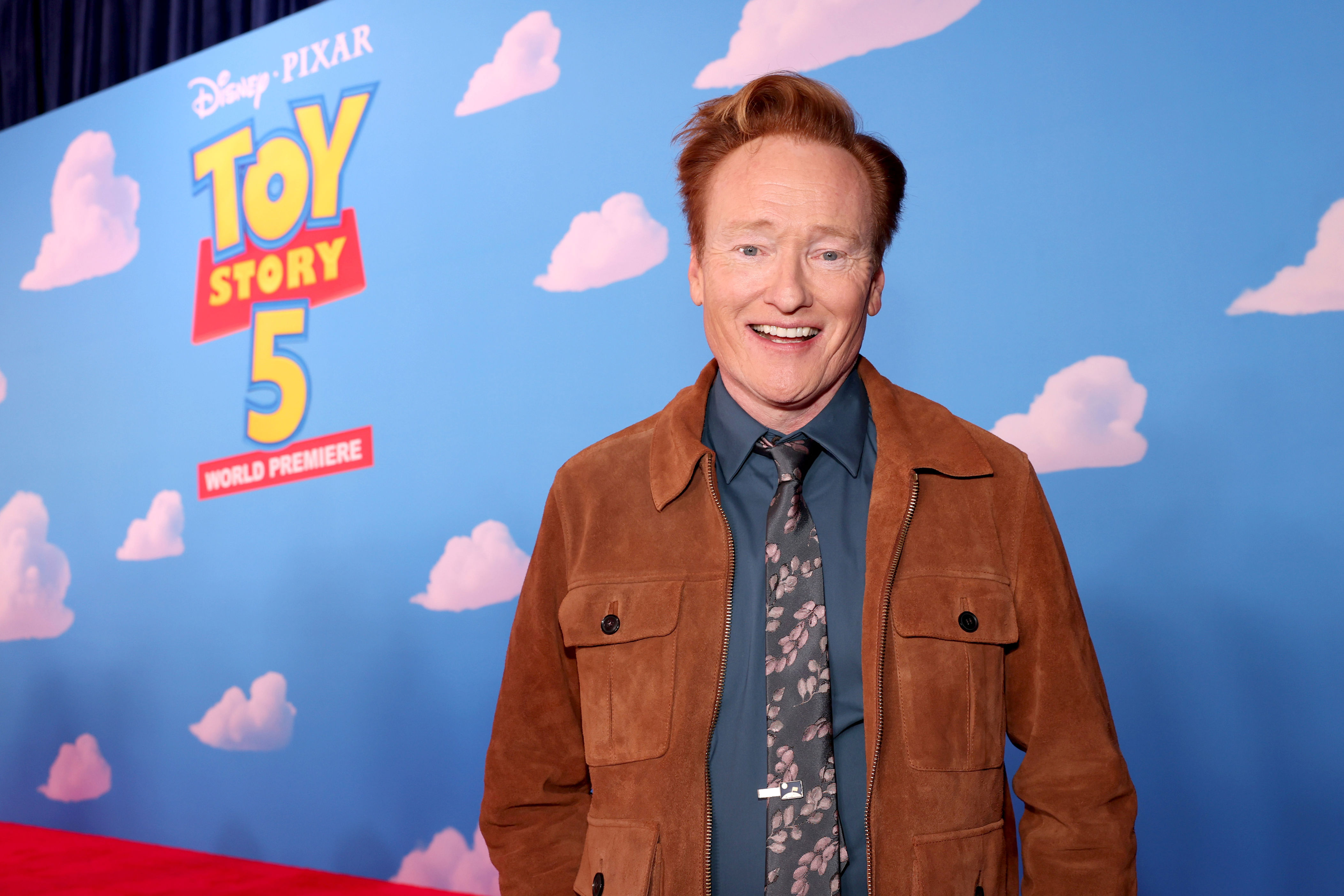Conan O'Brien smiling in front of a 