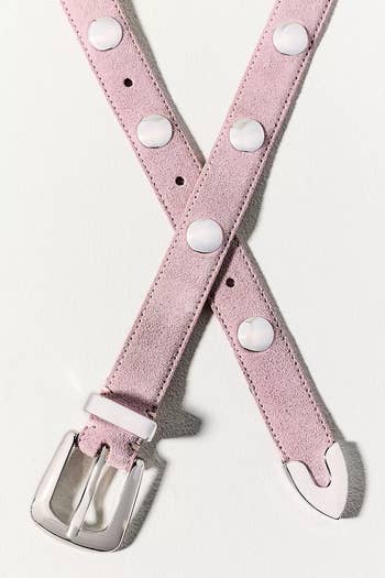 Suede belt with large round studs and a shiny metal buckle, laid out in a crisscross pattern