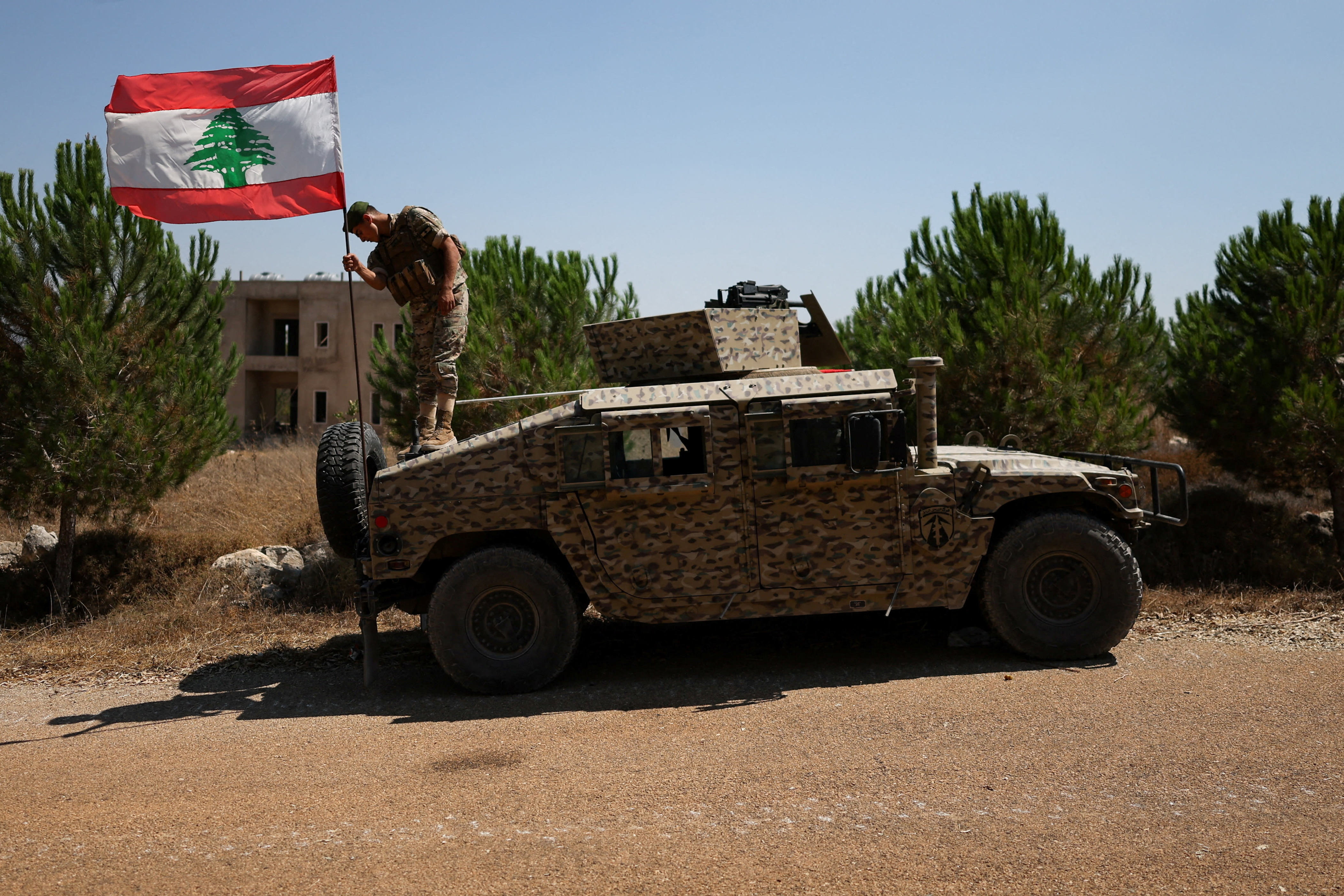 A soldier adjusts a Lebanese flag on an armored vehicle in Zawtar al-Gharbiyeh village, southern Lebanon, as Lebanese soldiers deploy in the area, July 21, 2026