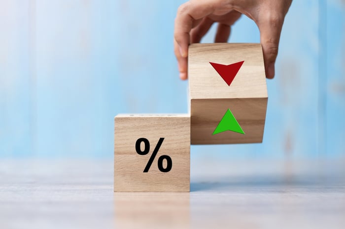 A block with a percent sign and a hand holding another brock with red and green arrows.