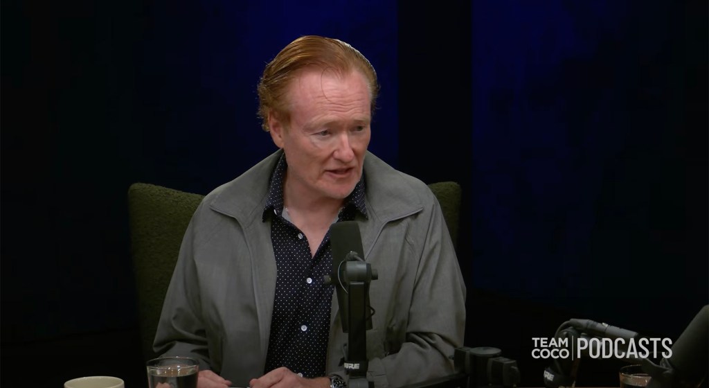 Conan O'Brien speaking into a microphone with