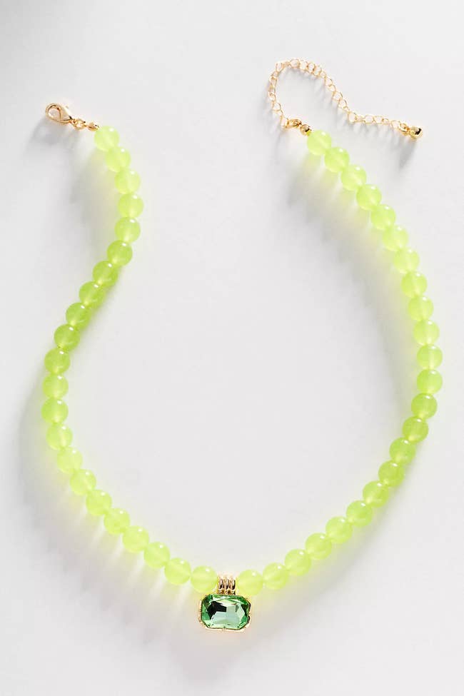 Beaded necklace with a green gemstone centerpiece and adjustable chain. Perfect for adding a touch of elegance to any outfit