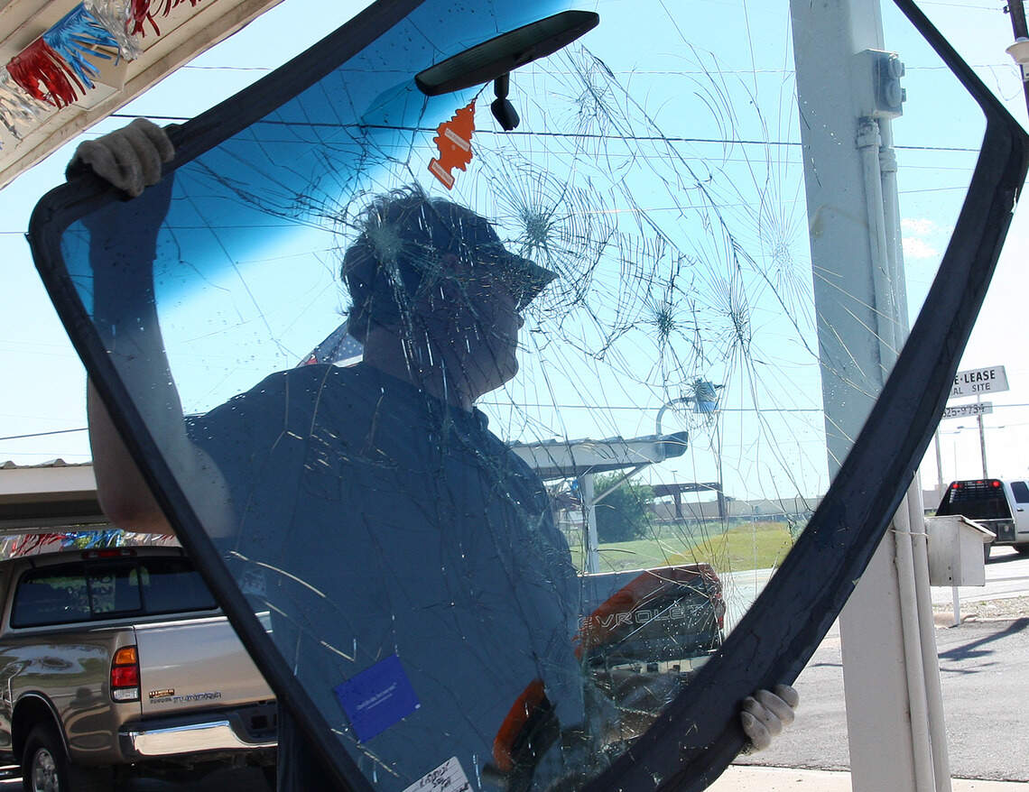 Ron Tobin of Tri-County Auto Glass in Azle, TX looks removes the damaged windshield from one of the vehicles in Mineral Wells on Friday April 18, 2008.