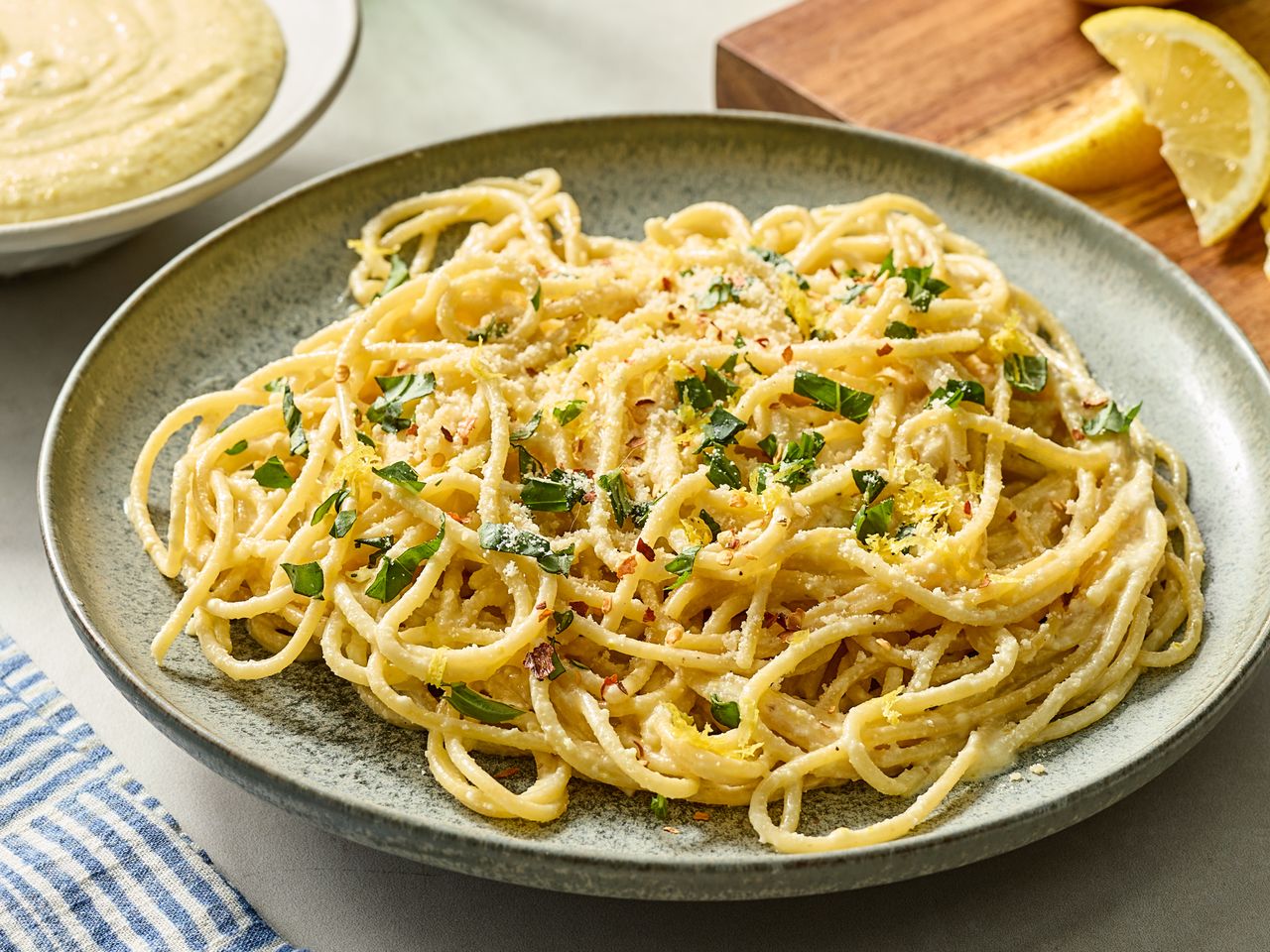 A dish of spaghetti with pesto sauce garnished with parsley and cheese