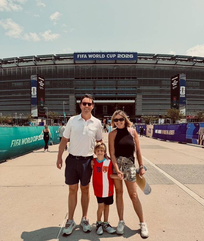 Jenna wearing shorts outside stadium with husband and son
