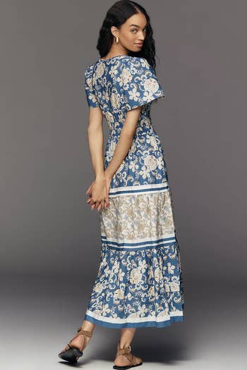 Model wearing a floral patterned maxi dress, looking over her shoulder