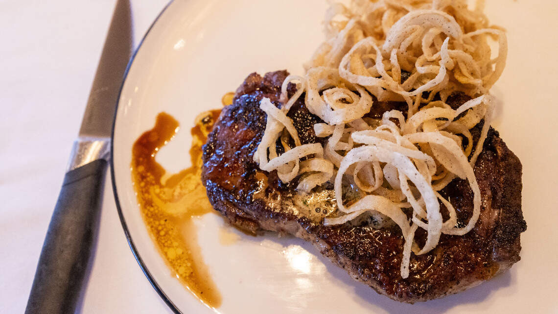 The 16-oz., 60 day dry-aged Kansas City NY Strip Steak ($78) at The V at the Vine comes with compound butter and fried onion straws.