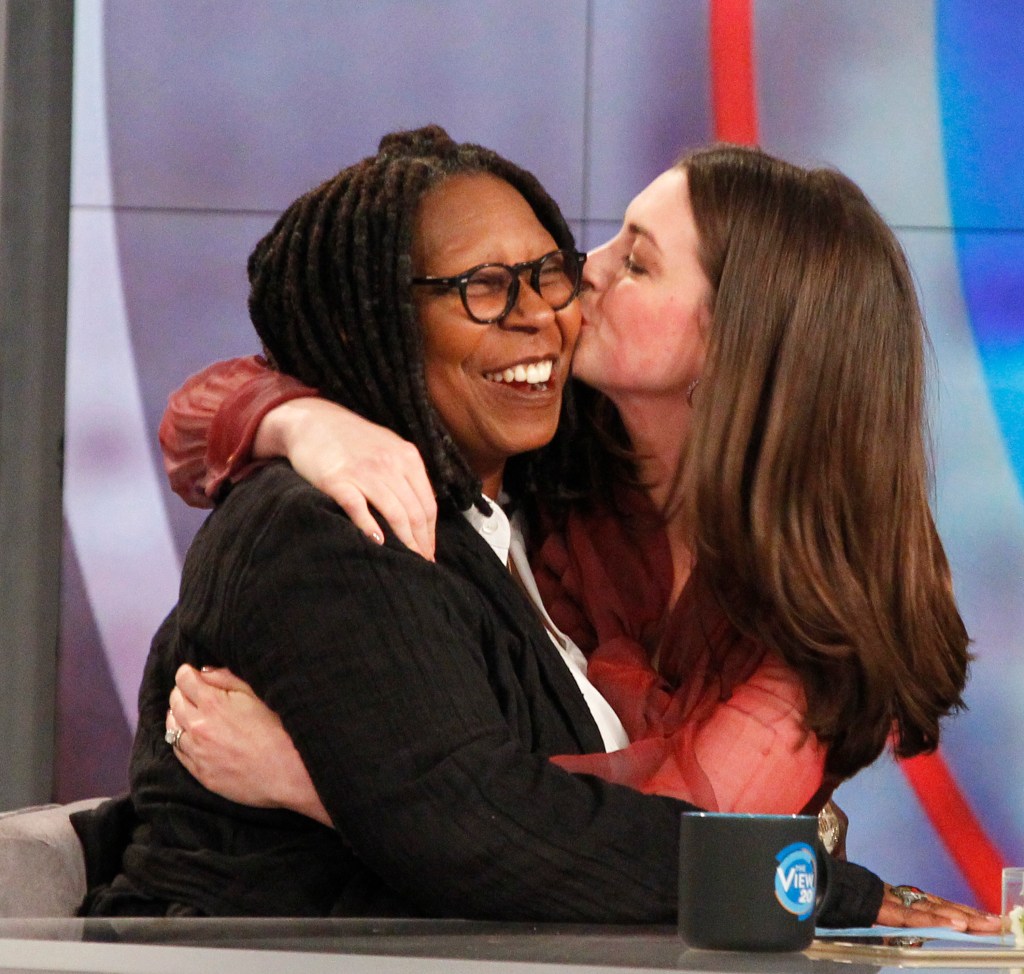 Anne Hathaway kissing Whoopi Goldberg on the cheek during an episode of