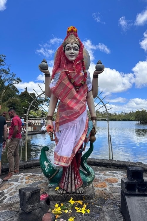 Serene view of Ganga Talao in Mauritius, surrounded by lush greenery and temple structures.