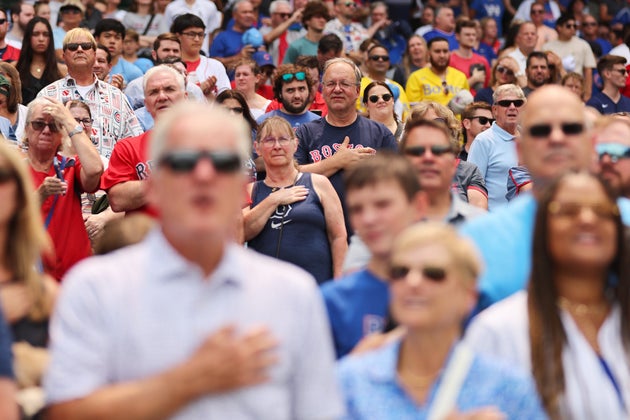 Fans at Wrigley Field observe the playing of the national anthem before the Cubs play the Red Sox in a 2023 game.
