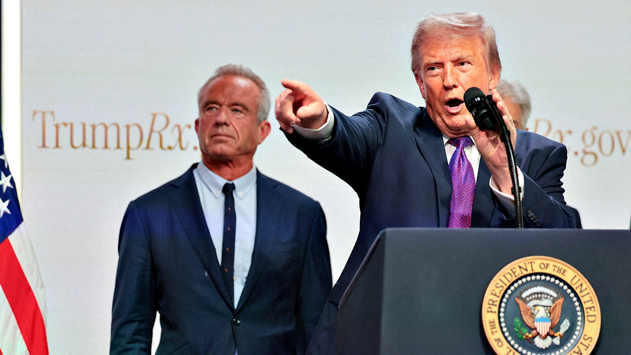 U.S. Health and Human Services Secretary Robert F. Kennedy Jr. stand behind U.S. President Donald Trump as he points while delivering remarks about health care costs and affordability from an auditorium on the White House campus in Washington, D.C., U.S., May 18, 2026.