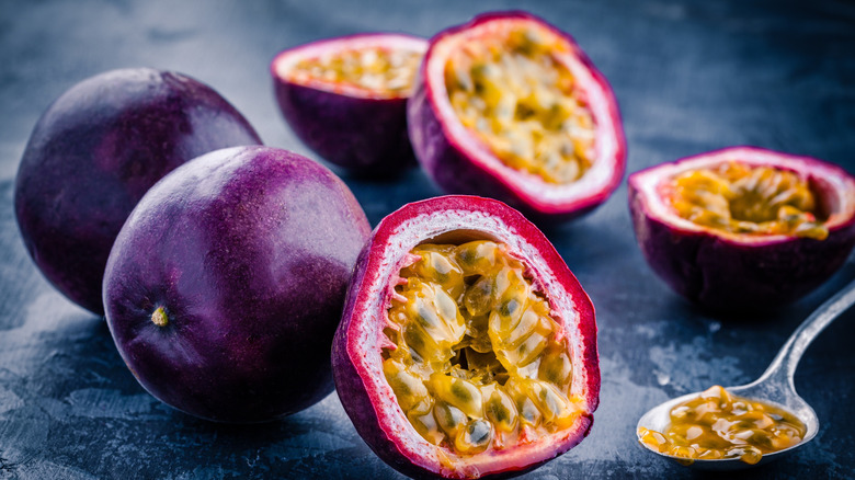 A few passion fruits on a table, whole and sliced open
