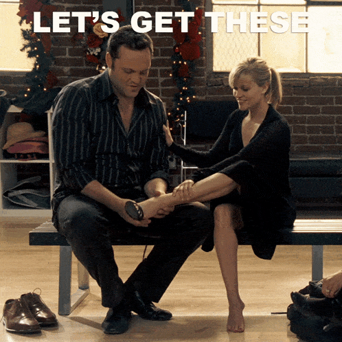 A man helps a woman try on shoes while sitting on a bench, with