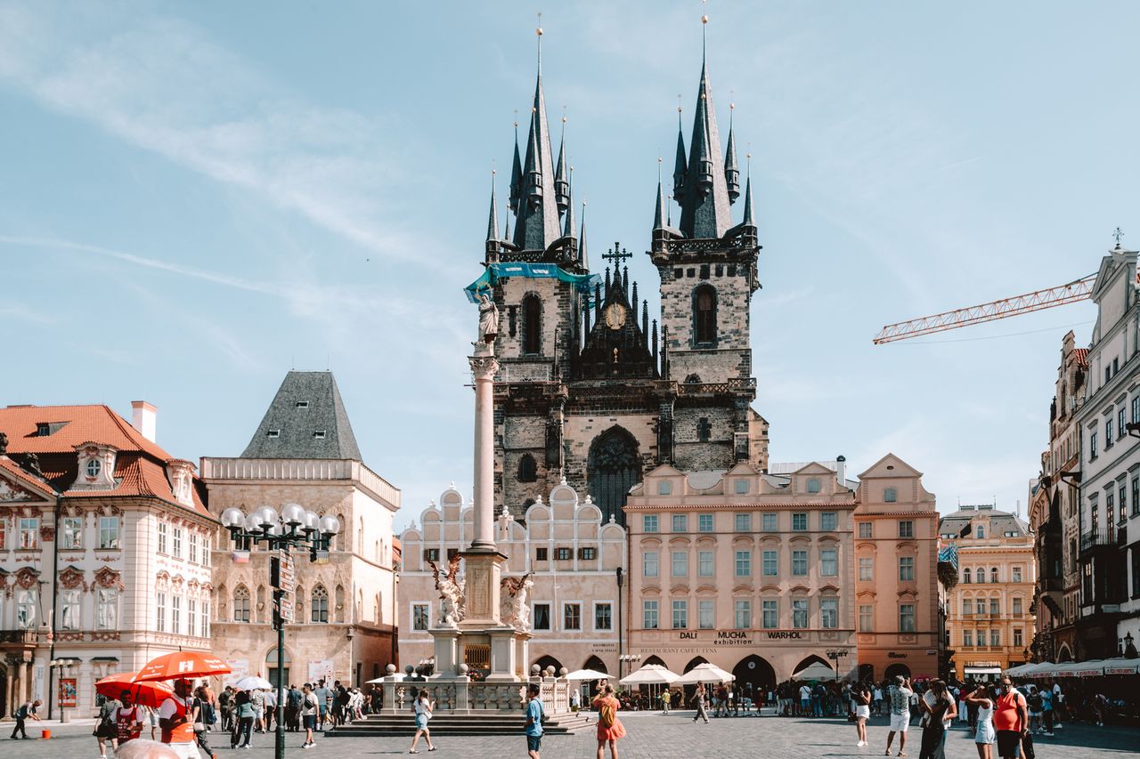 Tourists in a city square with historic buildings and a cathedral in the background