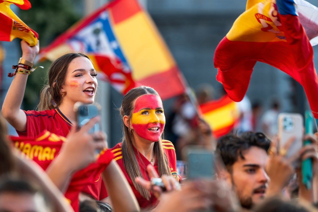 MADRID, SPAIN - 2026/07/20: Spanish football fans dressed in national red and yellow colors wave flags and cheer along the street at Plaza de Cibeles during the national team's World Cup victory parade. An estimated two million people flooded the capital's streets to welcome the squad following their 1-0 win against Argentina in the 2026 FIFA World Cup final. (Photo by Miguel Candela/SOPA Images/LightRocket via Getty Images)