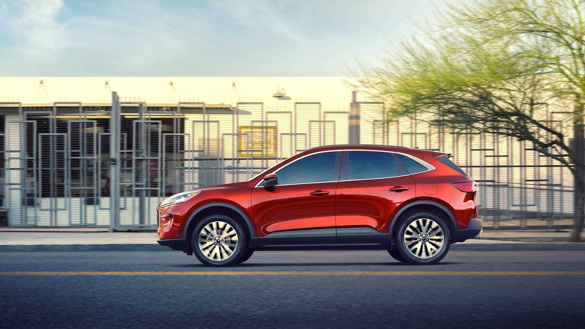 Discover the completely redesigned, sleek red 2020 Ford Escape parked in front of a building for promotional photo.