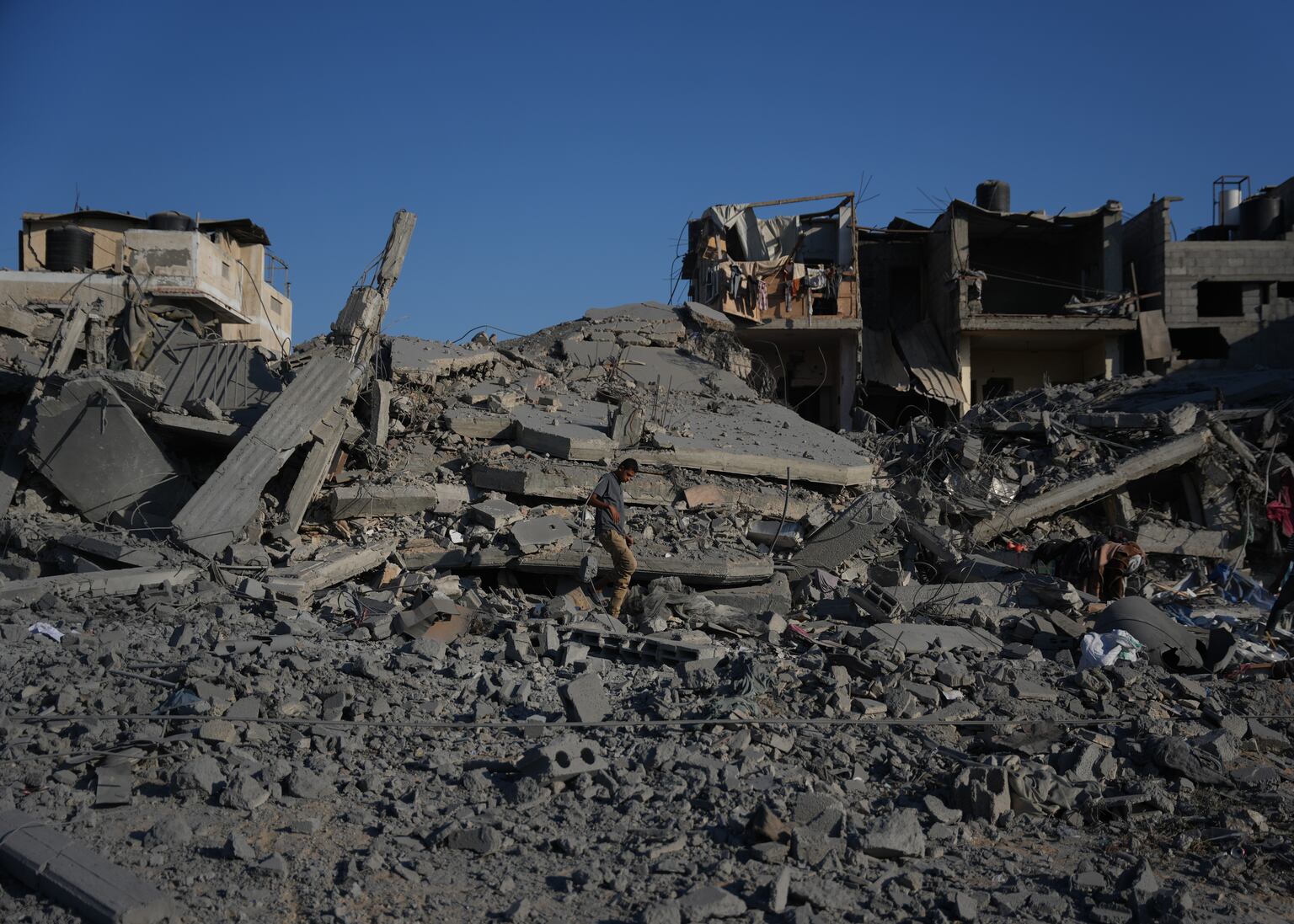 Palestinians inspect a destroyed building following an Israeli air strike in Deir al-Balah, central Gaza Strip (Abdel Kareem Hana/AP)