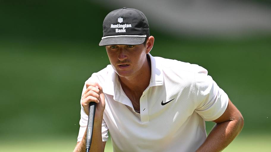 Preston Stout stands behind his golf ball to line up a putt.