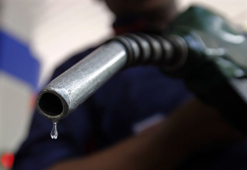 A worker holds a fuel nozzle at a petrol pump in Mumbai