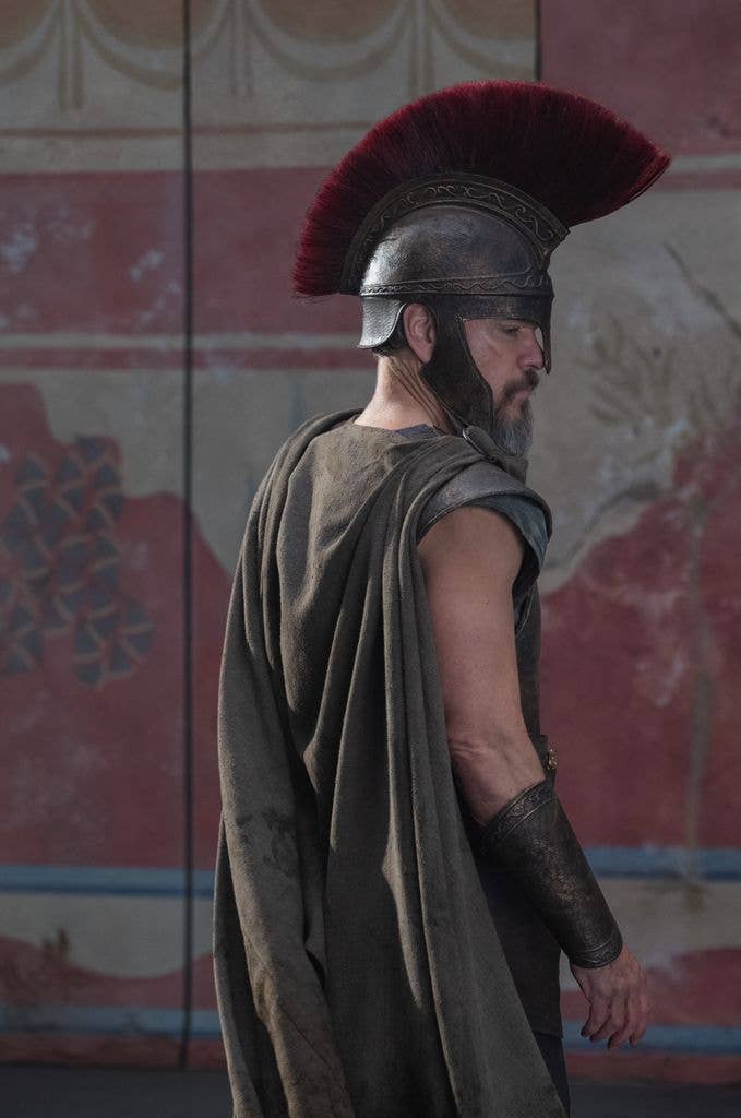 Matt Damon in ancient Roman soldier attire with red-plumed helmet and cloak.