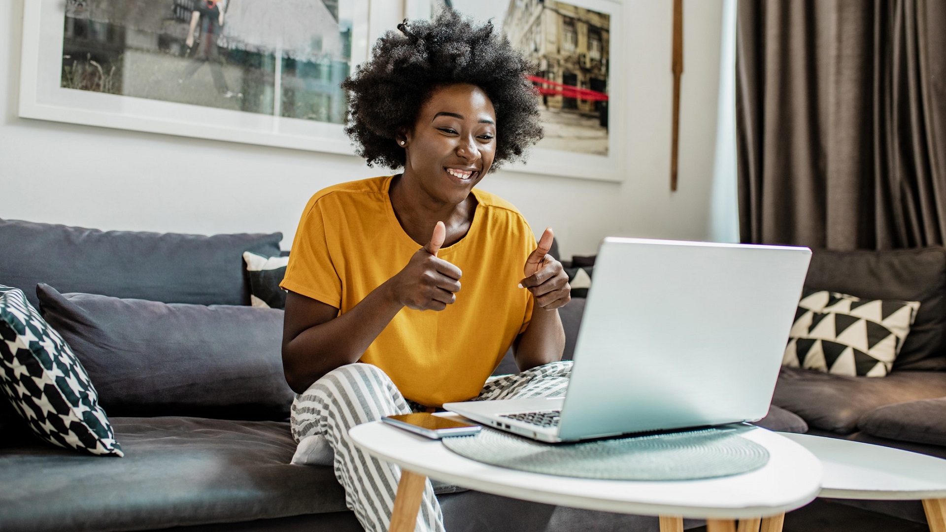 Discover a woman sitting on a couch in her living room interviewing for a remote job on her laptop computer