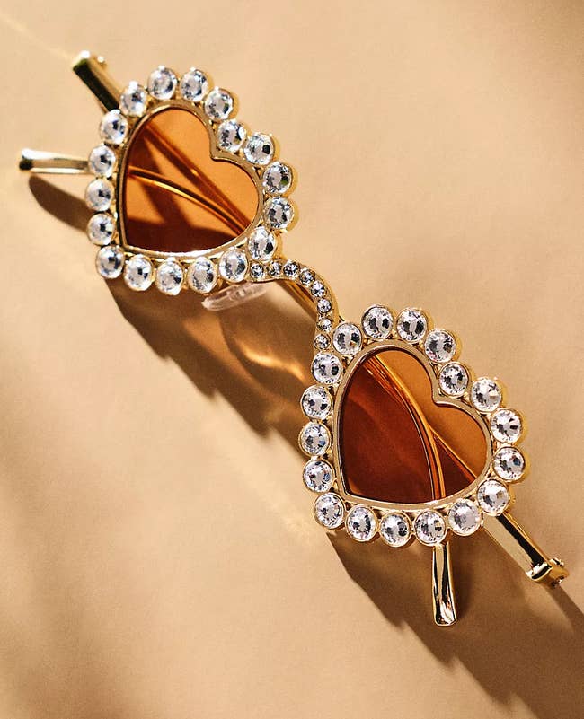 Heart-shaped sunglasses with rhinestone accents, designed for a stylish, playful look. Featured in a shopping context