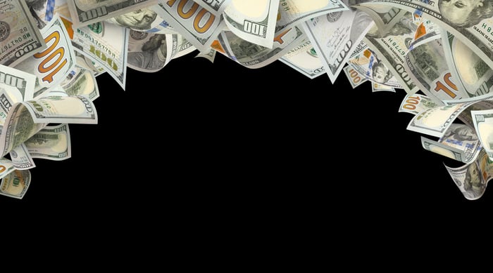 Stream of $100 bills flying through the air in an arc.