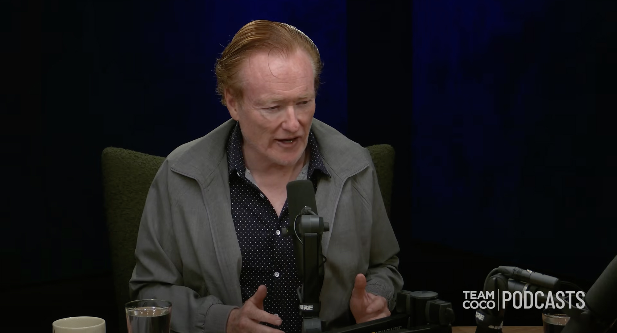Conan O'Brien speaking into a microphone.
