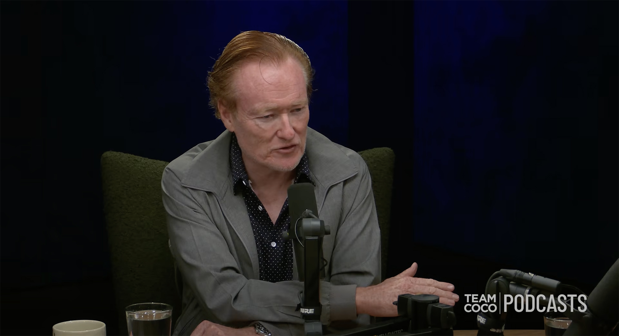 Conan O'Brien speaking into a microphone.