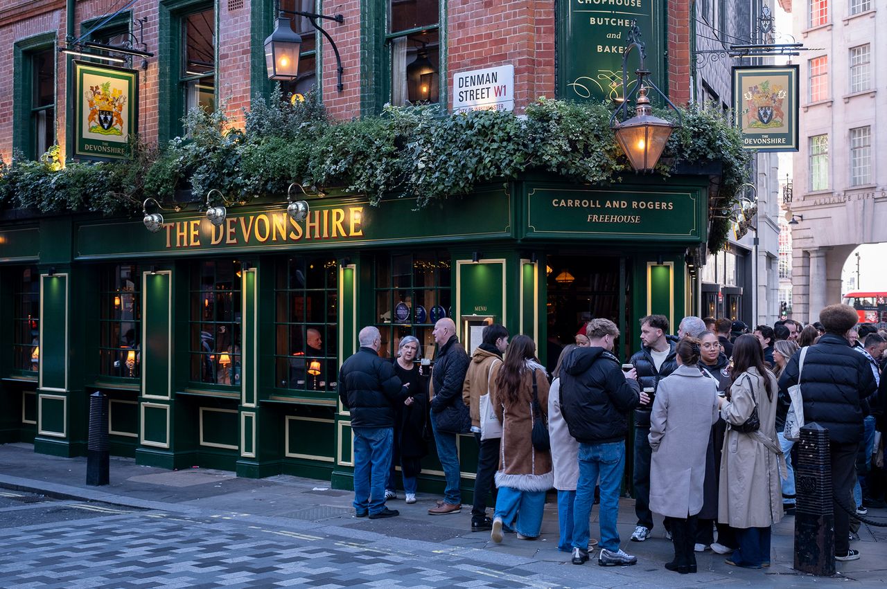A crowd of people gathered outside The Devonshire pub in a city street