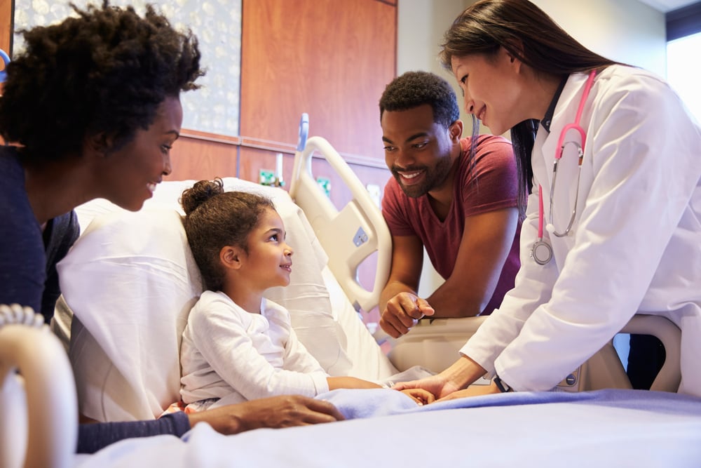 Pediatrician Visiting Parents And Child In Hospital Bed