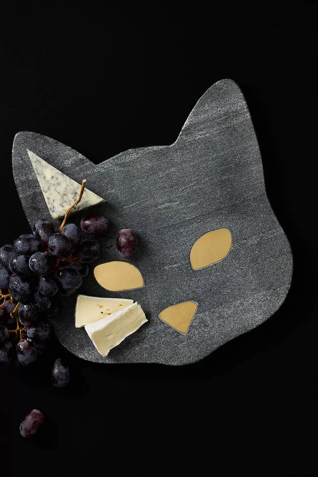 Cat-shaped cheese board with grapes and cheese wedges arranged on top