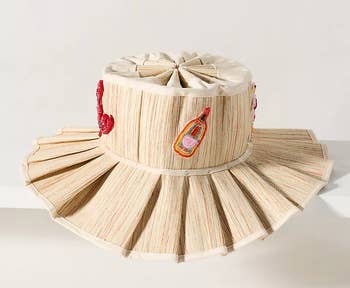 Wide-brimmed straw hat with decorative stitching and embroidery, featuring a unique pleated design around the brim, perfect for chic sun protection
